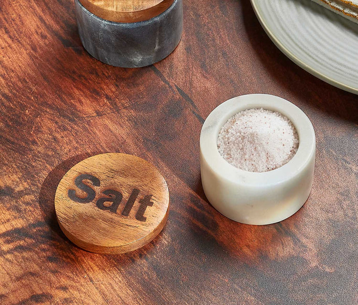 Salt container with wooden lid on a wooden surface