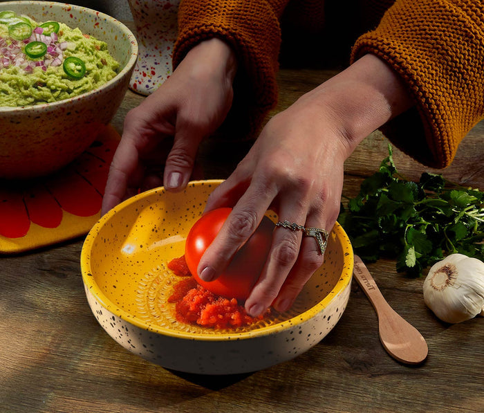 Yellow cinnamon grater bowl in use preparing guacamole with fresh tomato - Lollygag