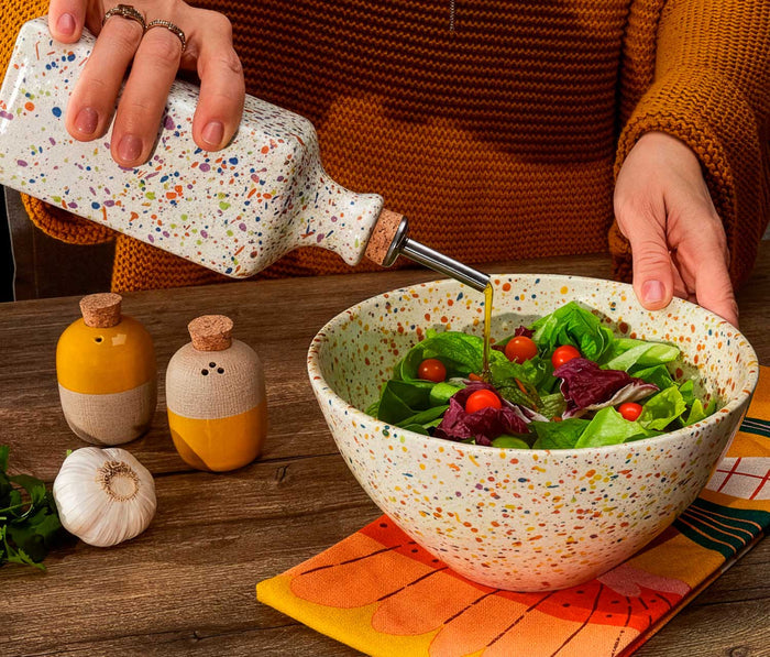Person pouring olive oil into a salad bowl with a Confetti oil cruet - lollygag
