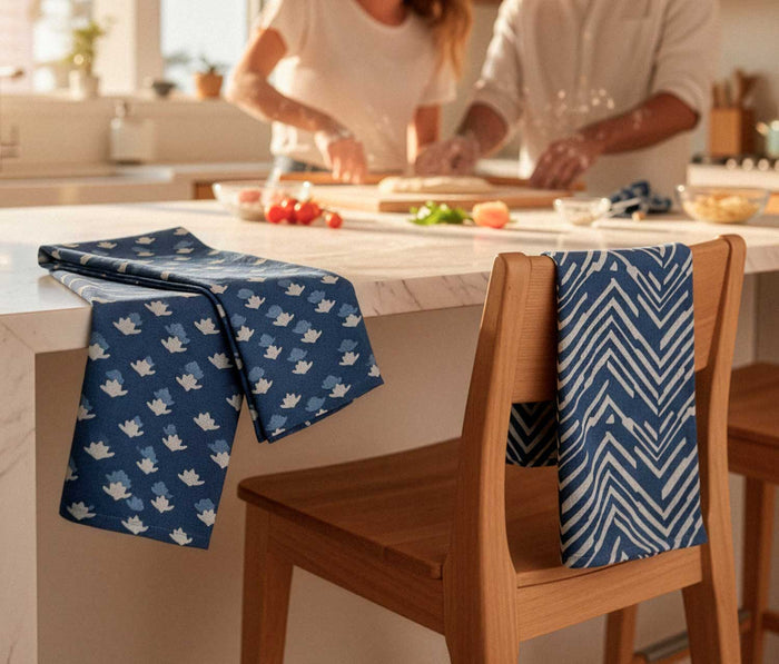 Two indigo patterned towels hanging on wooden chairs in a kitchen.