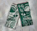 Set of 2 Wildgrove evergreen and ivory mushroom-print dishtowels by Danica Studio, folded on a textured surface