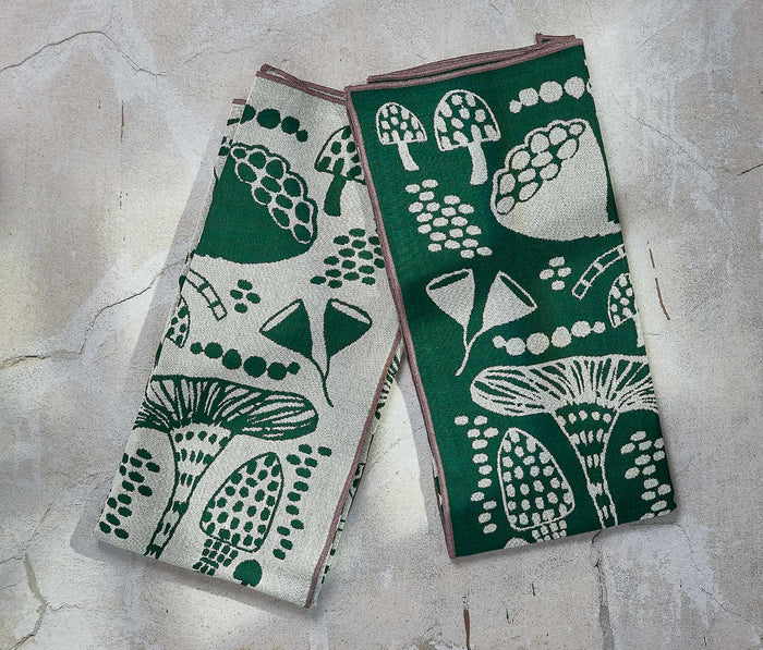 Set of 2 Wildgrove evergreen and ivory mushroom-print dishtowels by Danica Studio, folded on a textured surface